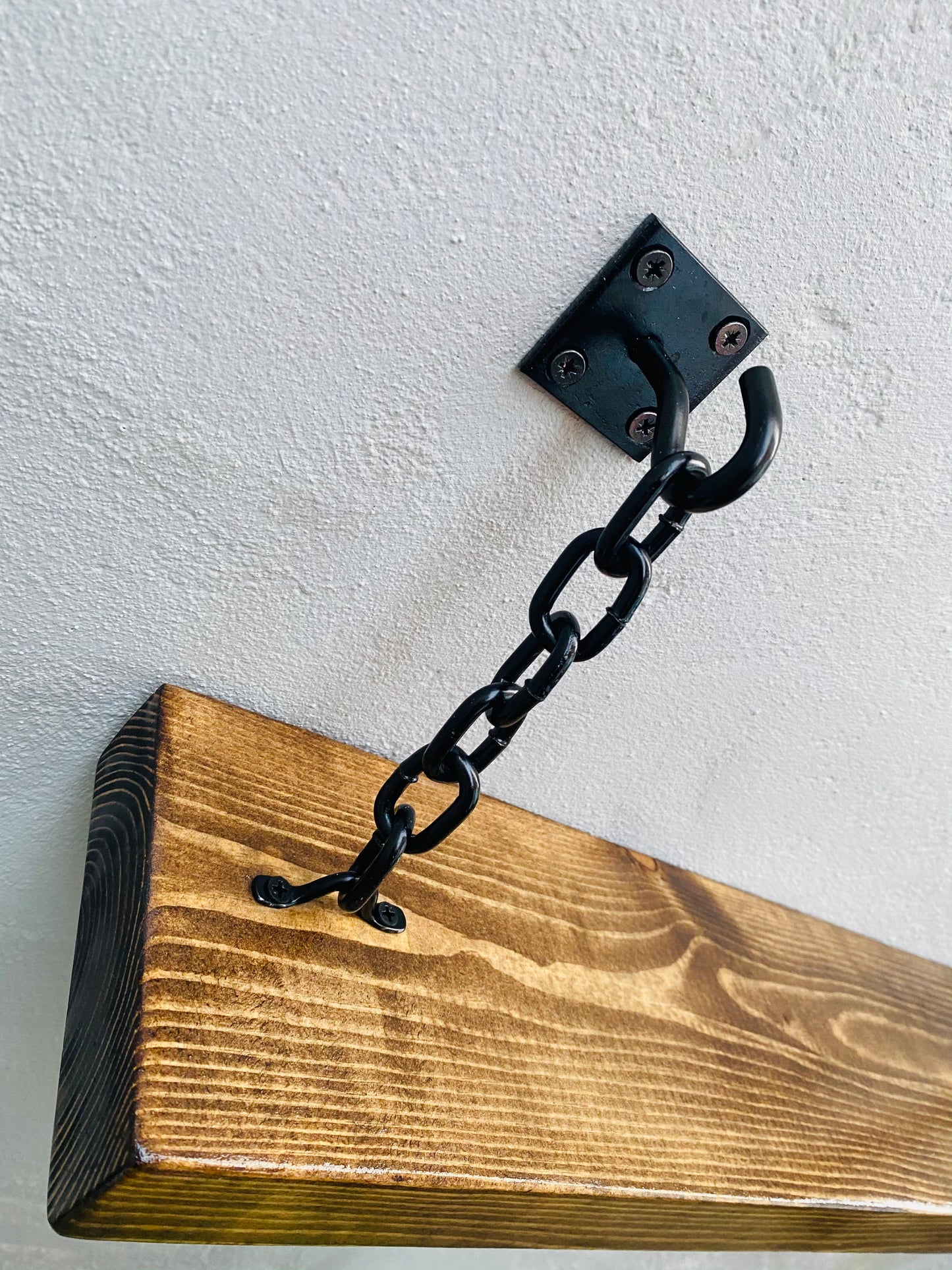 Black hook and chain shelf bracket attached to a wood shelf