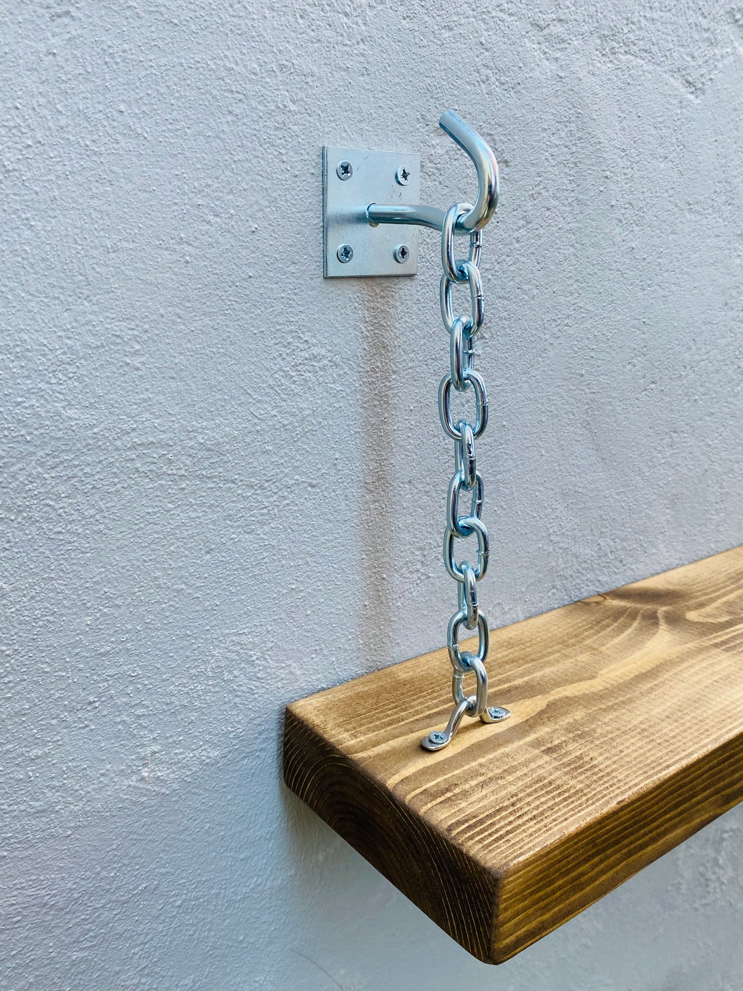 Close up of chrome hook and chain shelf brackets wall mounted