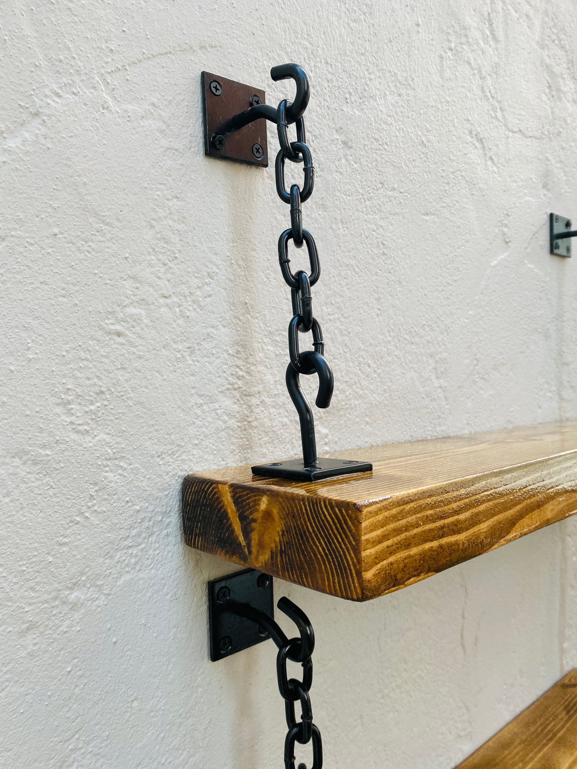 handmade wooden shelves supported by black metal chain brackets