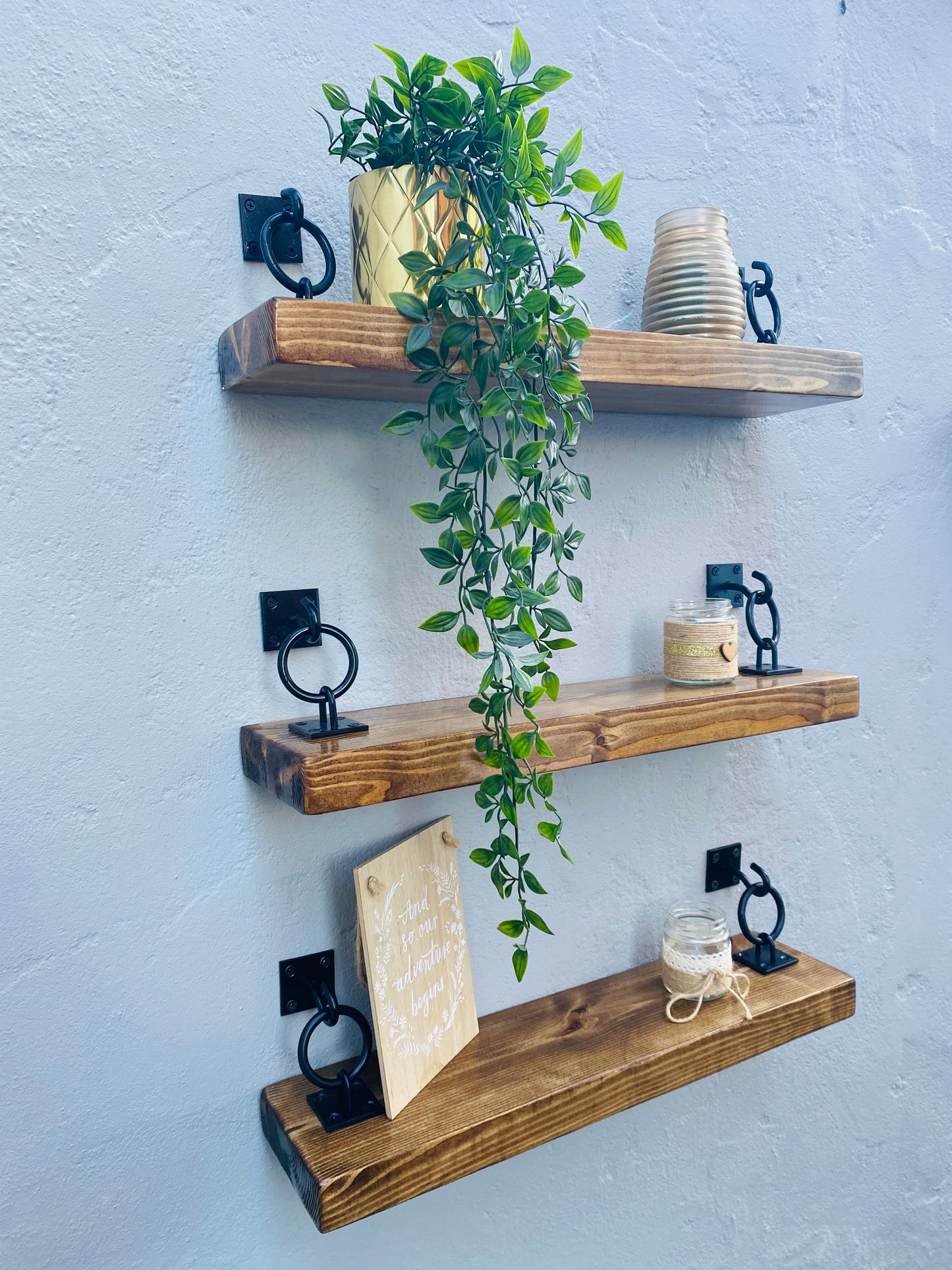 three -tier wooden floating shelves with black ring brackets
