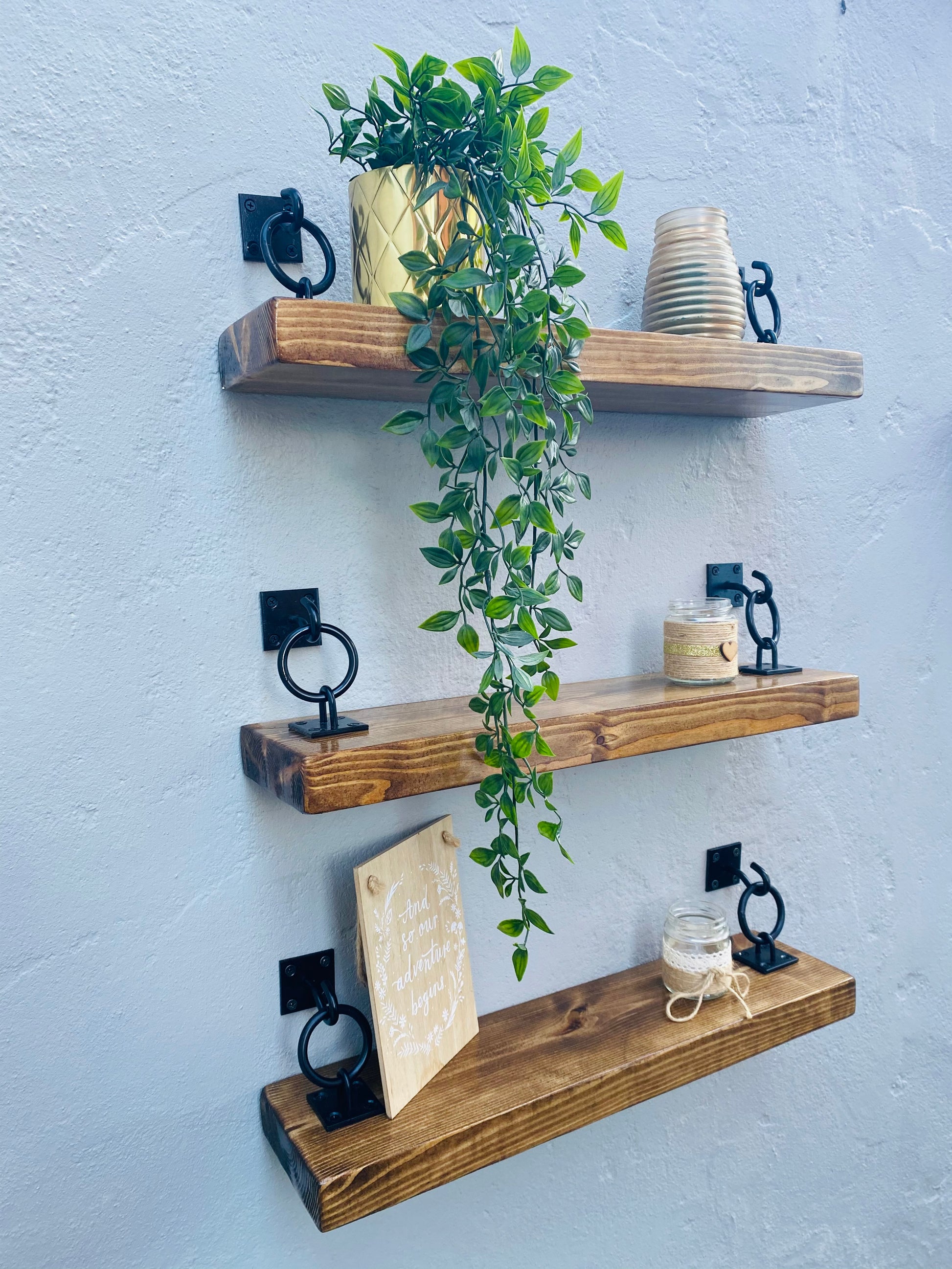three -tier wooden floating shelves with black ring brackets